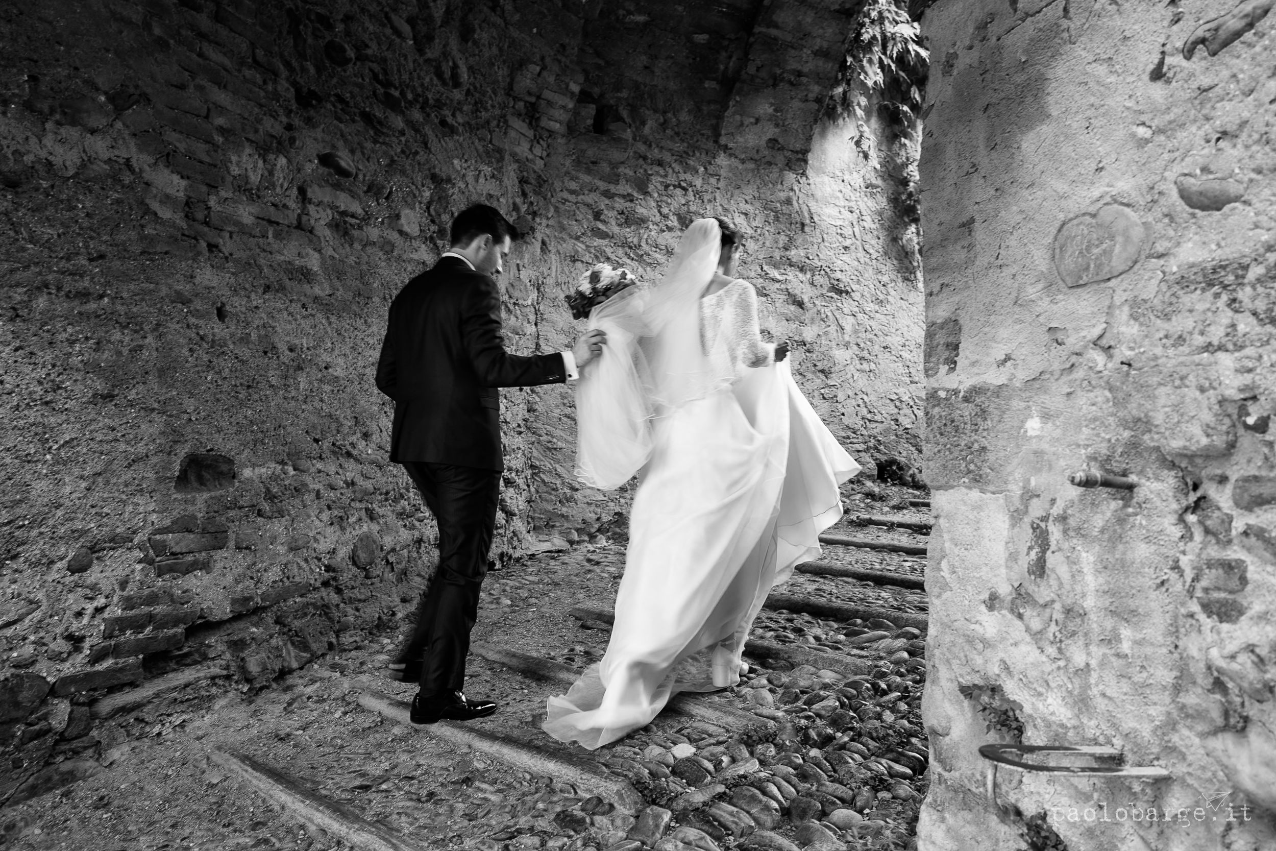 Two figures ascend a stone staircase in what appears to be a historic castle or fortress interior.