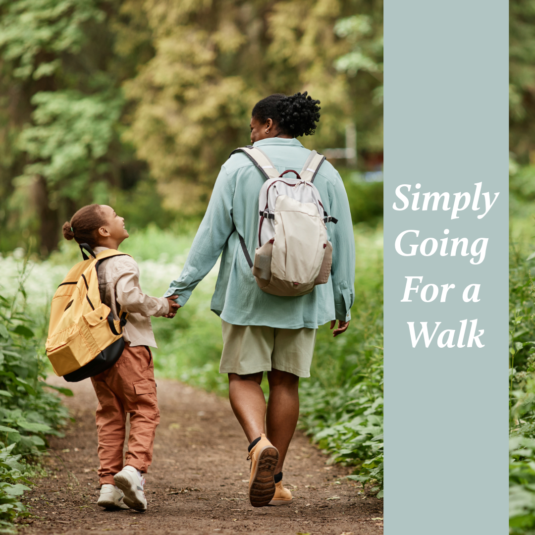 Two people with backpacks holding hands while walking together on a nature trail through lush green forest.