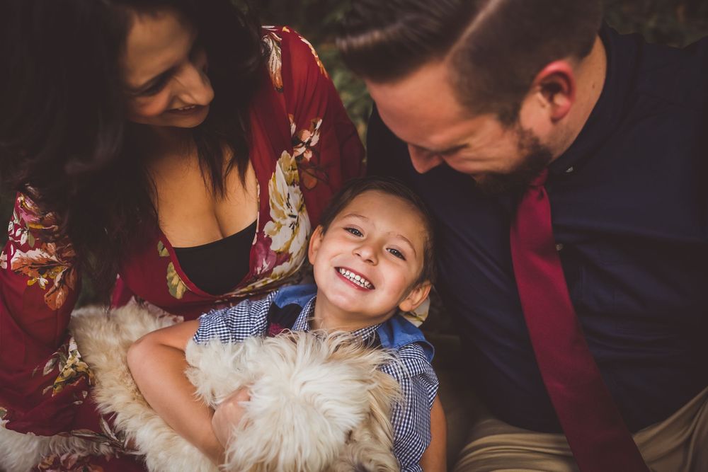 A joyful family moment captured with a child laughing while being tickled with a stuffed animal toy.