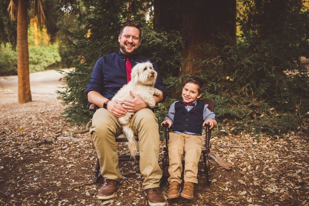 Five connected outdoor family photos featuring a white dog on fallen leaves in a wooded setting.