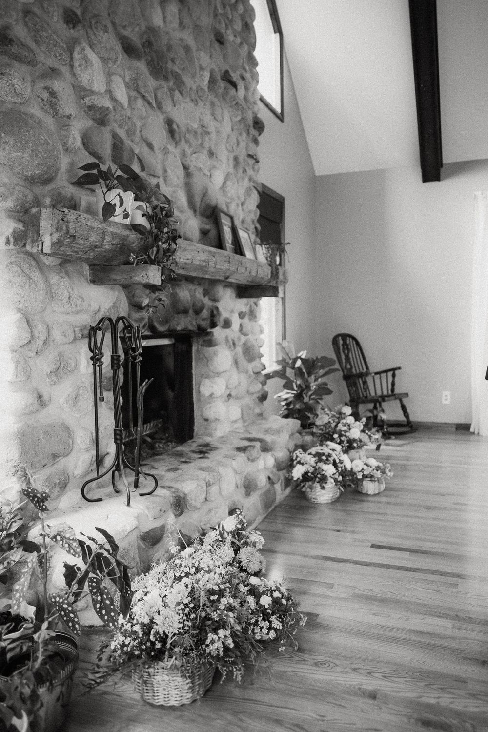 Black and white photo of rustic stone wall room interior with floral arrangements decorating the space.
