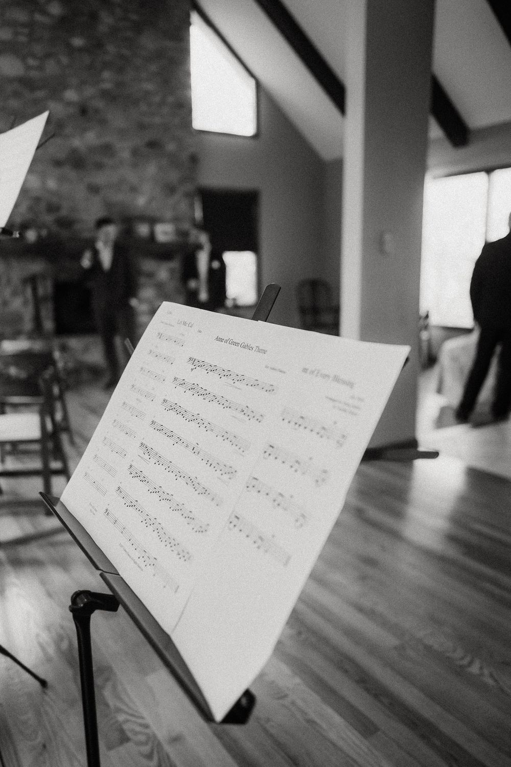 Sheet music on a music stand during a wedding ceremony with soft lighting and wood flooring.