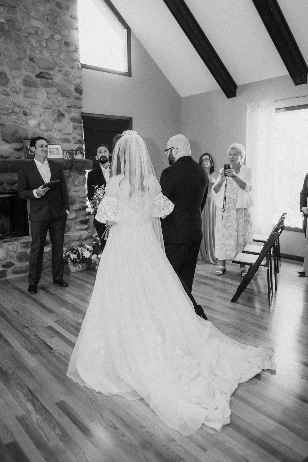 A wedding ceremony taking place in a rustic room with stone walls and exposed beams on the ceiling.