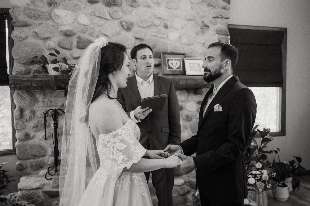 Wedding ceremony taking place in a rustic stone wall venue with natural lighting.