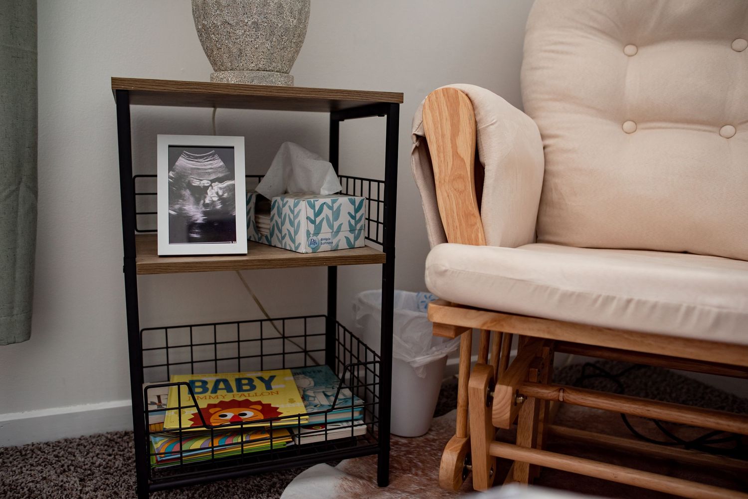 Cozy corner featuring a rocking chair with beige cushions, black shelving unit, and decorative accents in warm tones.
