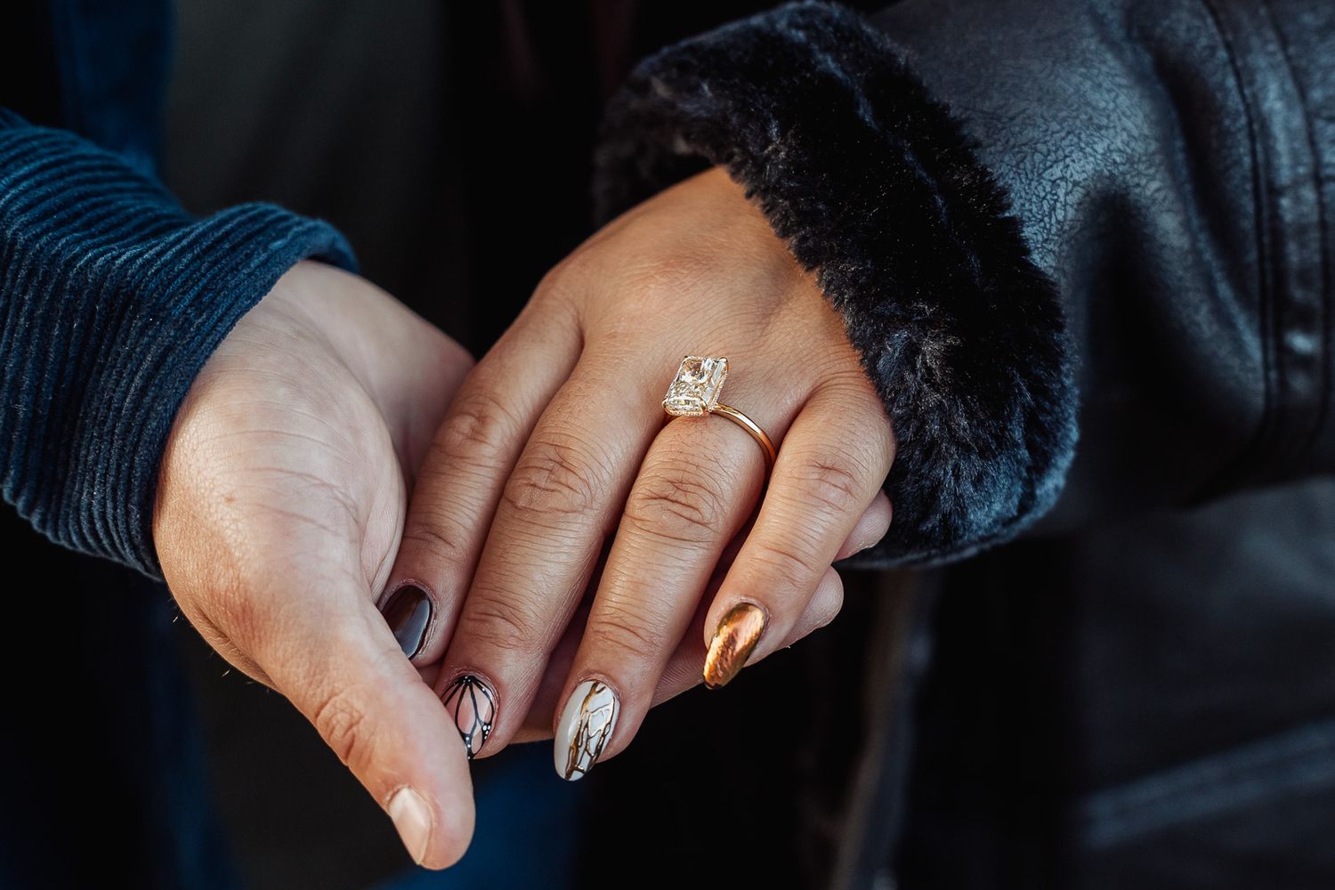 Close-up of manicured hand wearing engagement ring with sparkly nail polish.