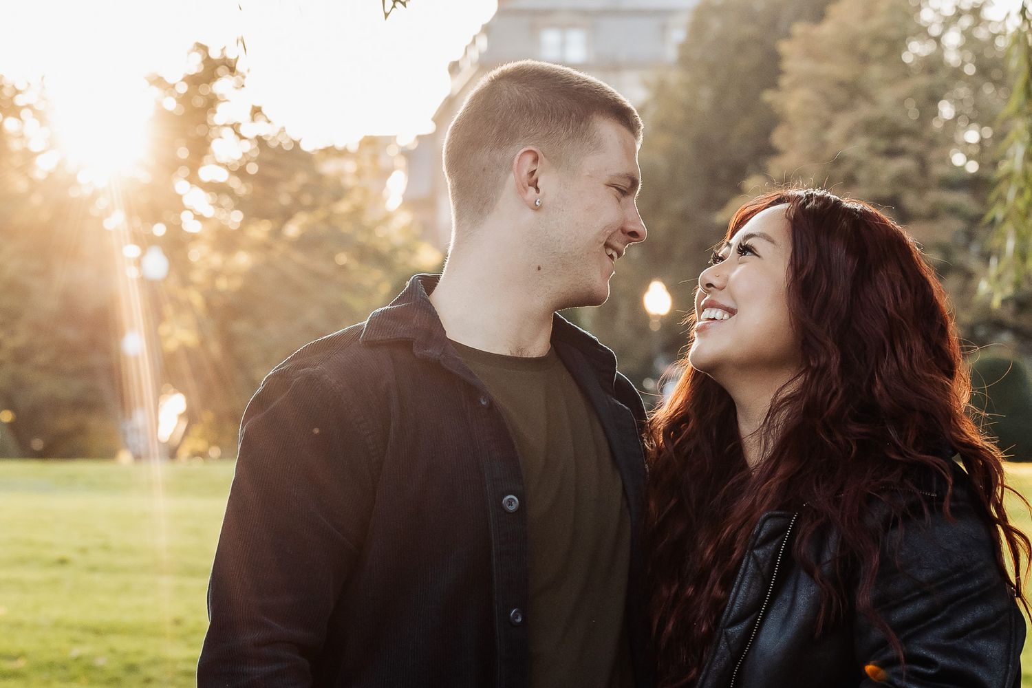 Couple laughing together in sunlit park during golden hour.