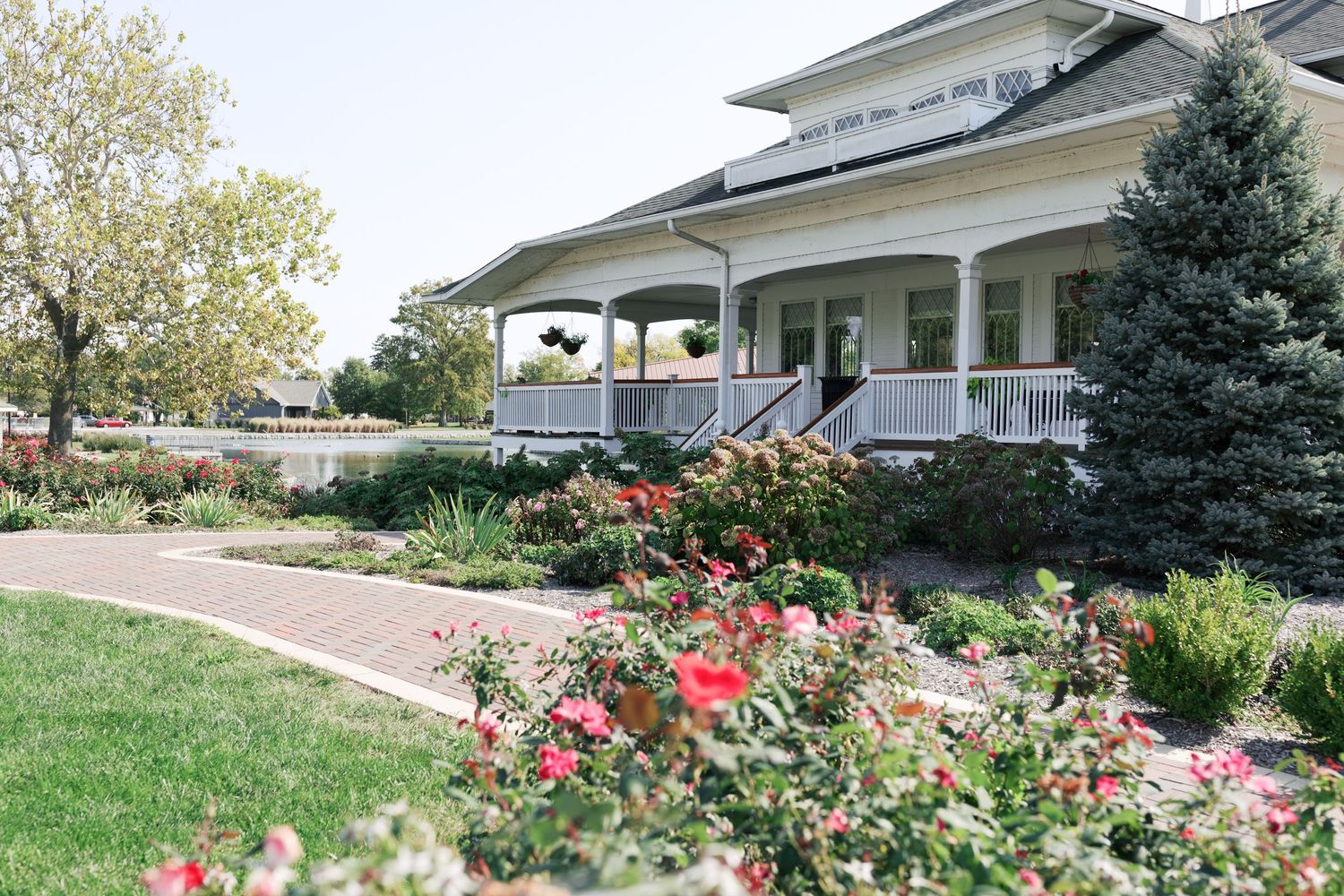 Charming craftsman style house with wraparound porch and colorful rose garden landscaping.