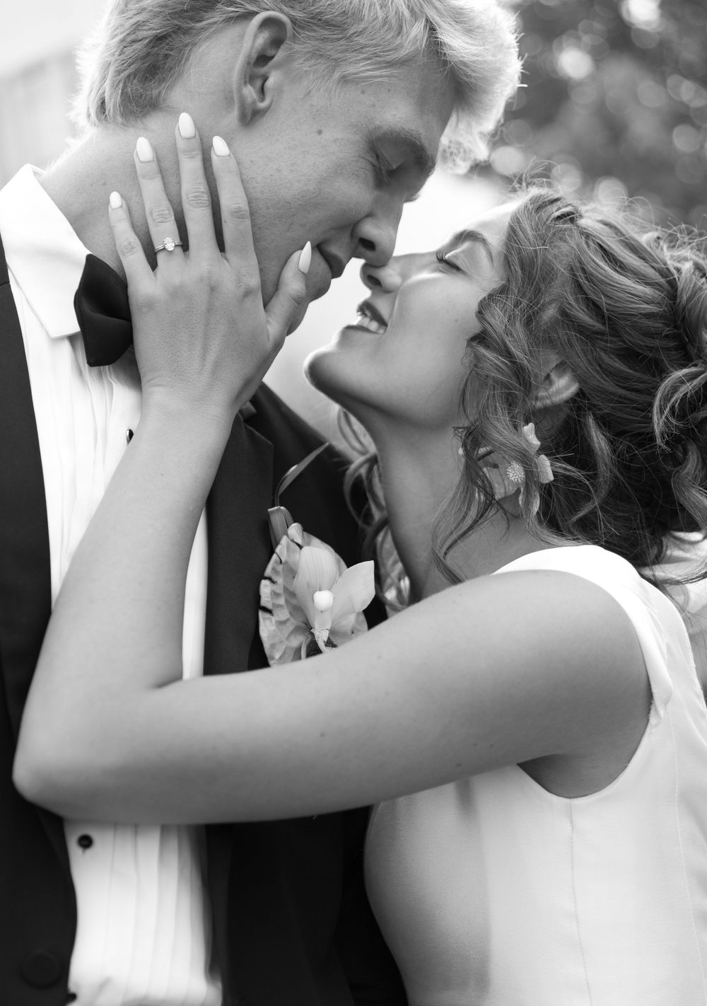 A romantic black and white photograph of newlyweds sharing an intimate moment on their wedding day.