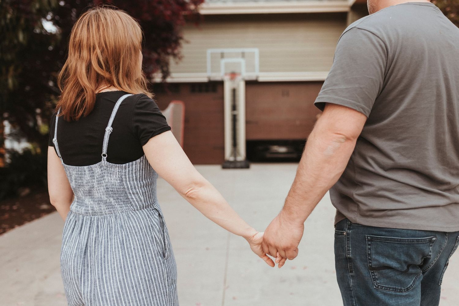 a husband and wife hold hands in the front yard of their home. Surrey BC Elizabeth Lang Photography