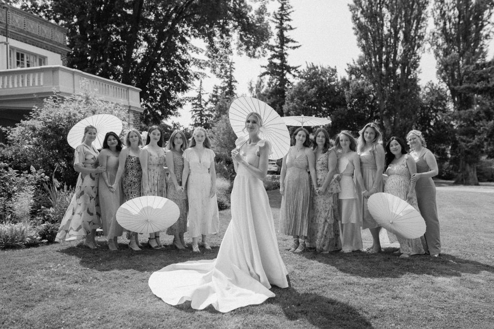 Elegant black and white vintage wedding photograph showing a bridal party gathered outdoors on a lawn.