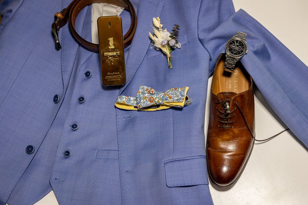 Light blue suit jacket displayed with brown leather shoes and wedding accessories.