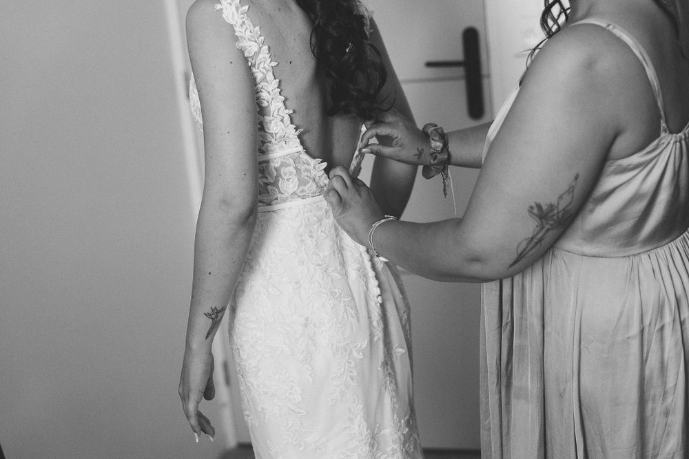 Final adjustments being made to an elegant white lace wedding dress.