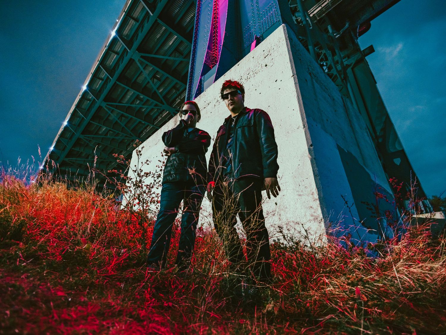 Artistic portrait of two figures against blue sky with vibrant red foliage.