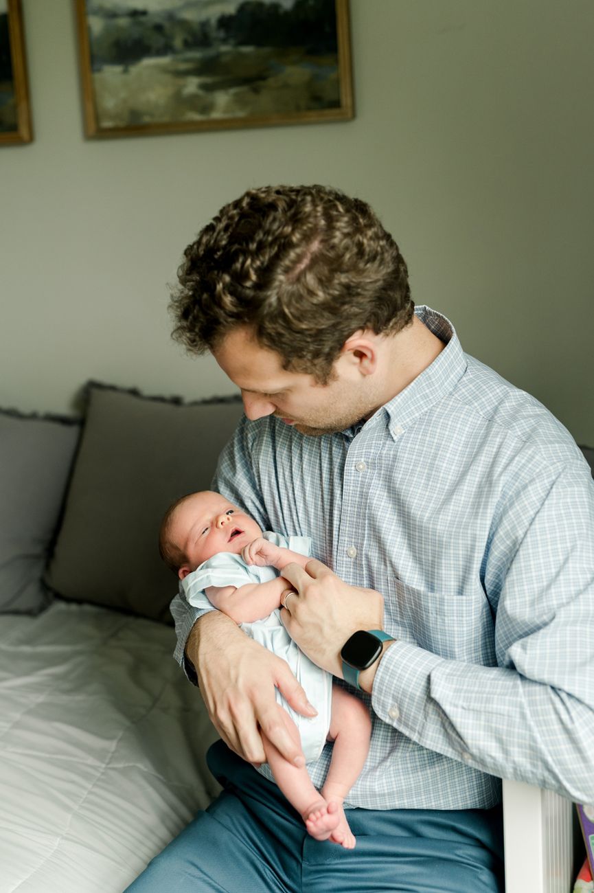 A tender moment showing a baby being cradled and comforted while resting on a couch with gray pillows.