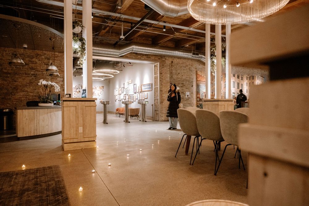 Modern industrial office space with exposed brick walls, polished floors, and stylish pendant lighting in a warm brown ambiance.