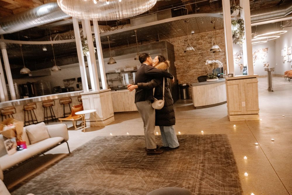 A couple shares a romantic dance on a vintage rug in an industrial-style venue with exposed brick walls and pillars.