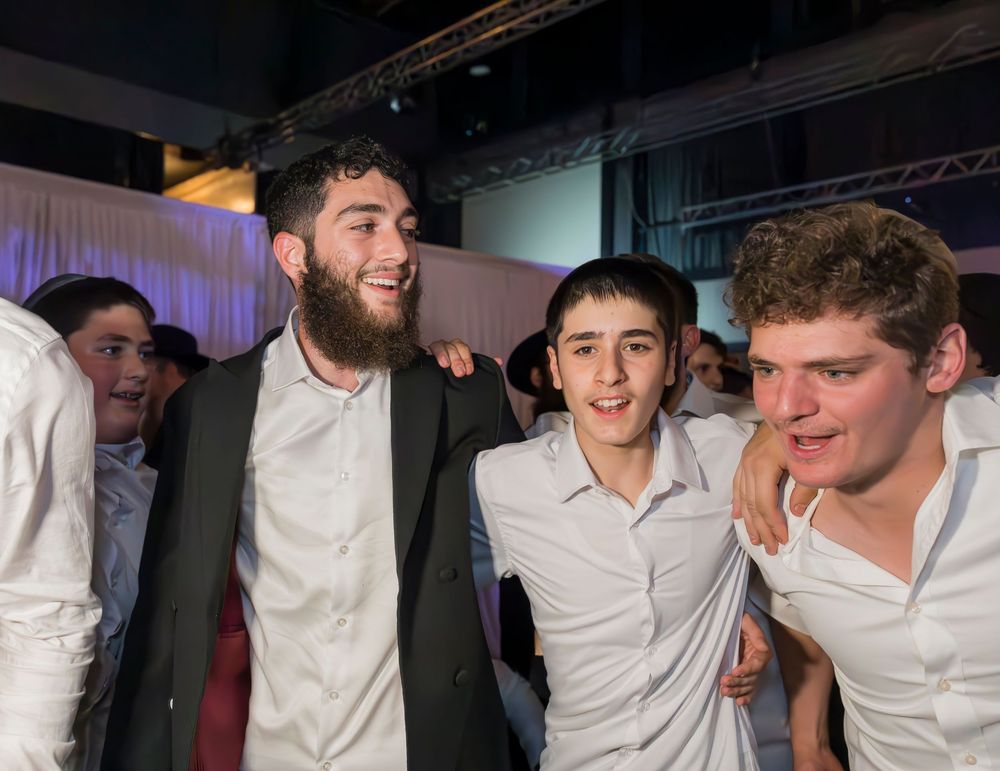 A group of young people wearing white shirts laugh and smile together at a social gathering.