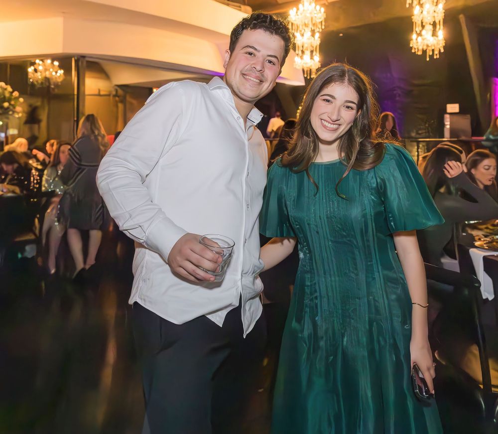 Two guests enjoying a formal evening event with elegant chandeliers and a festive atmosphere.