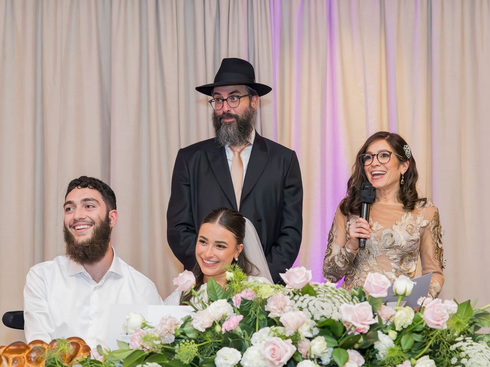 Wedding celebration with guests seated at an elegant table decorated with white floral centerpieces.