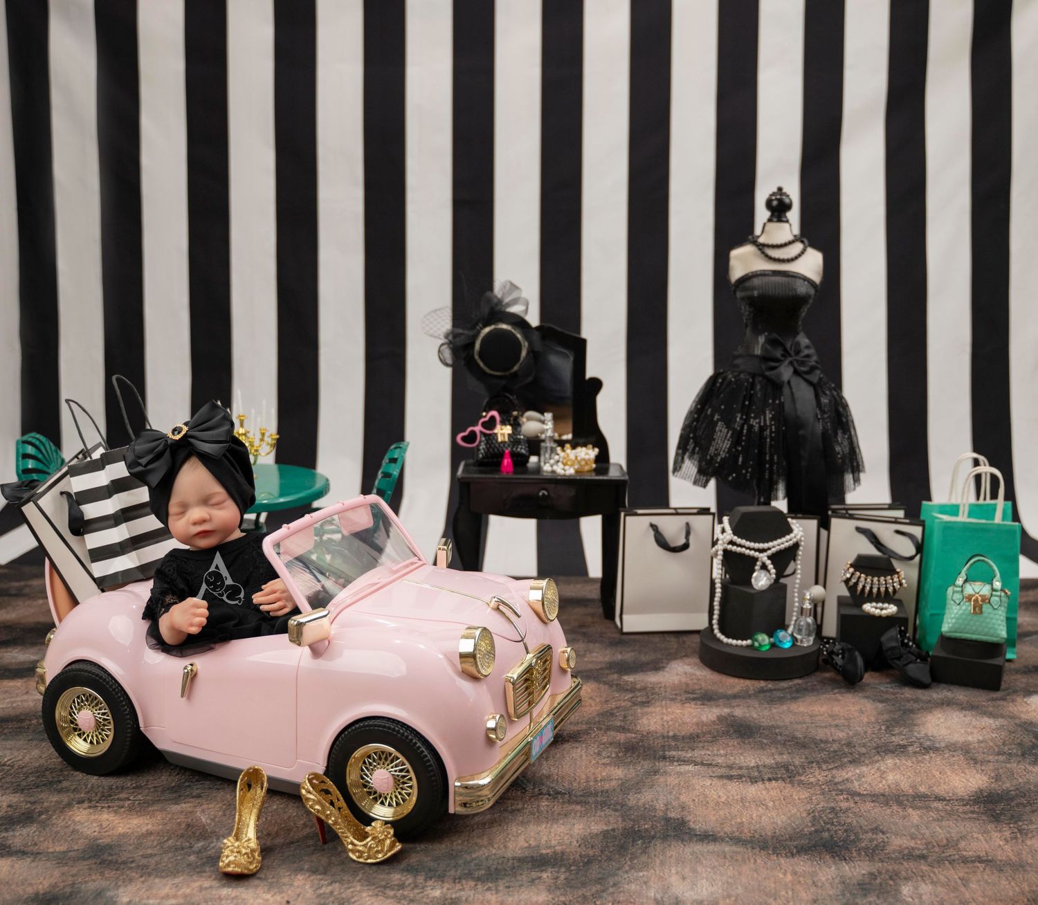 Pink toy car photo setup against black and white striped background with fashion accessories.