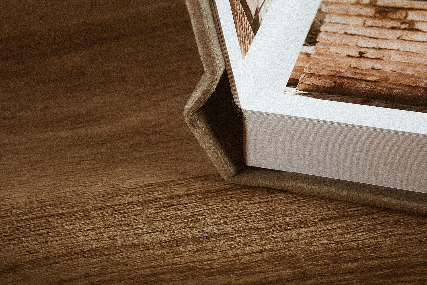 White photo frame corners rest against textured brown wooden surface, creating minimal composition.