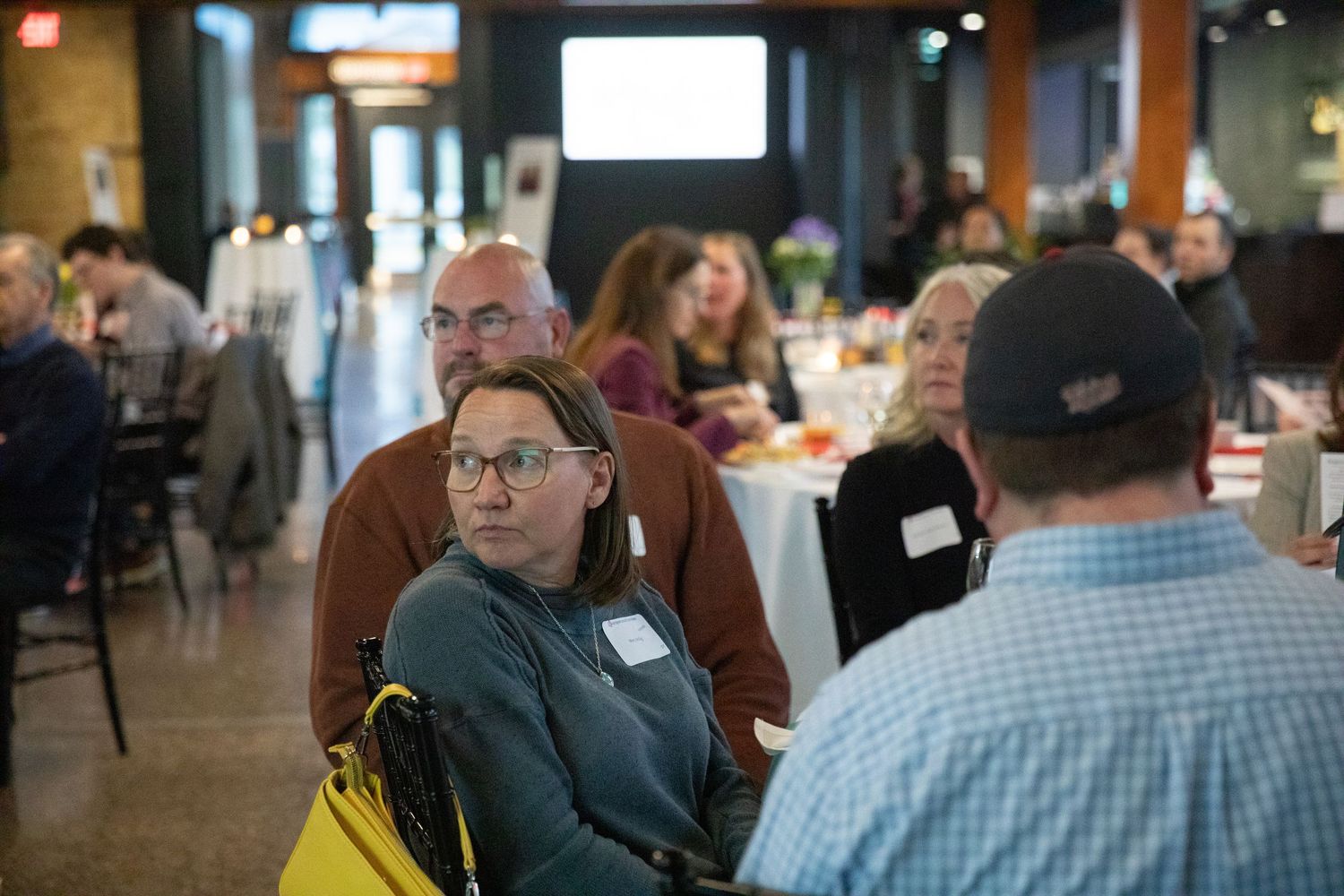 Attendees engage in conversation during a networking event at a rustic venue with exposed brick walls and warm lighting.