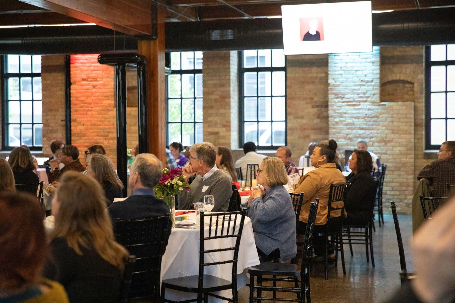 Professional gathering in a modern industrial space with exposed brick walls and elegant table settings.
