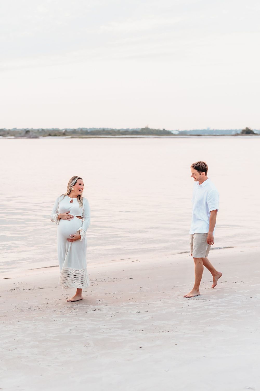 Expectant couple walking barefoot along a serene beach during a maternity photoshoot. Sunset Wrightsville beach wilmington nc