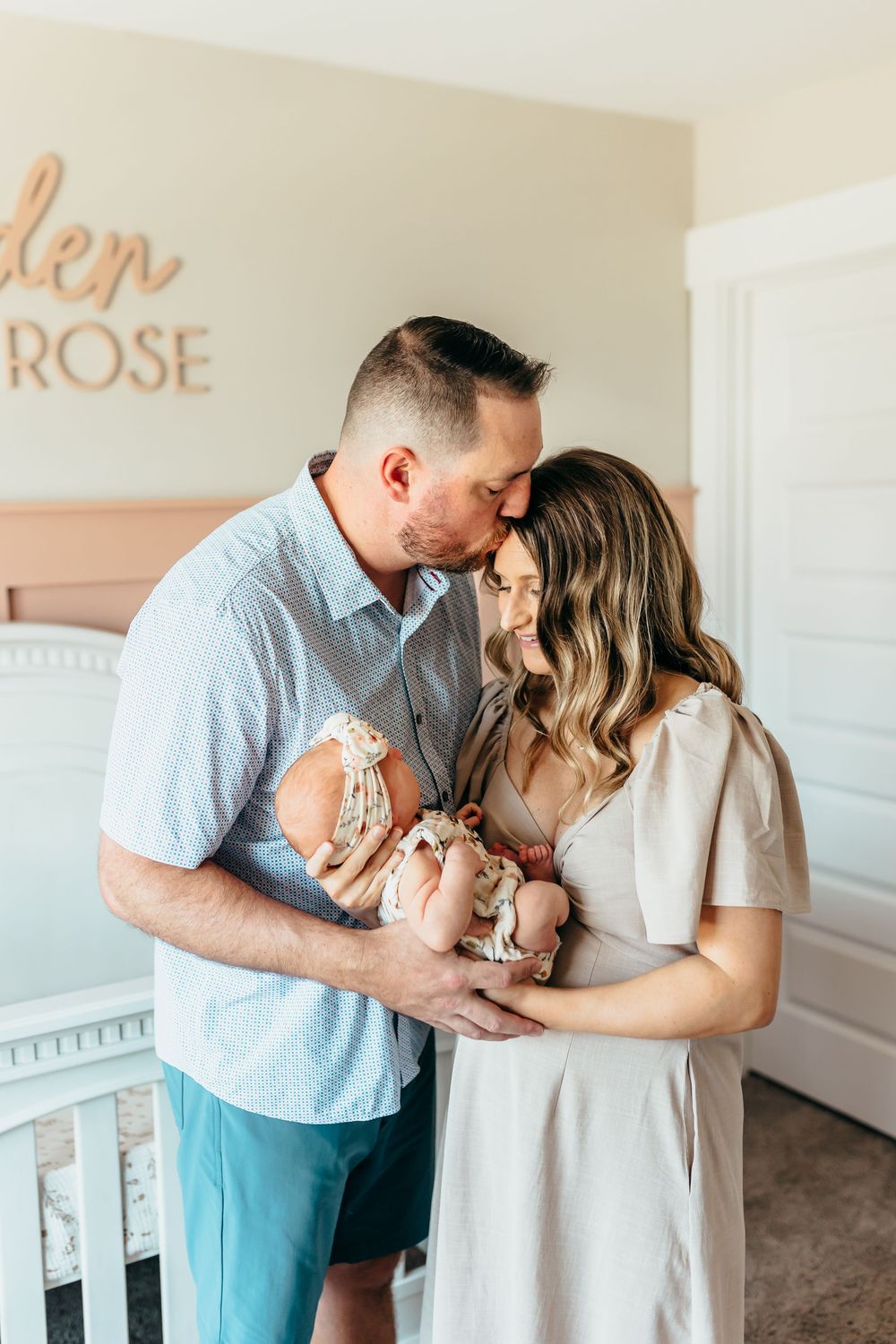 A couple in soft blue and white outfits share tender moments with their newborn in a series of intimate photos at home.