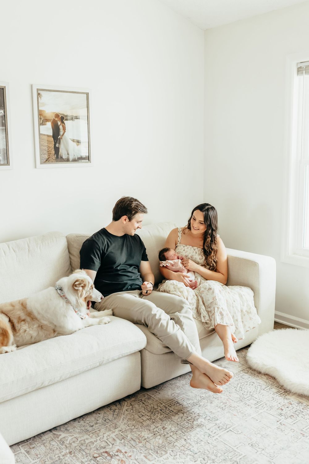 Family relaxing together on a white sectional sofa in a bright, minimalist living room.