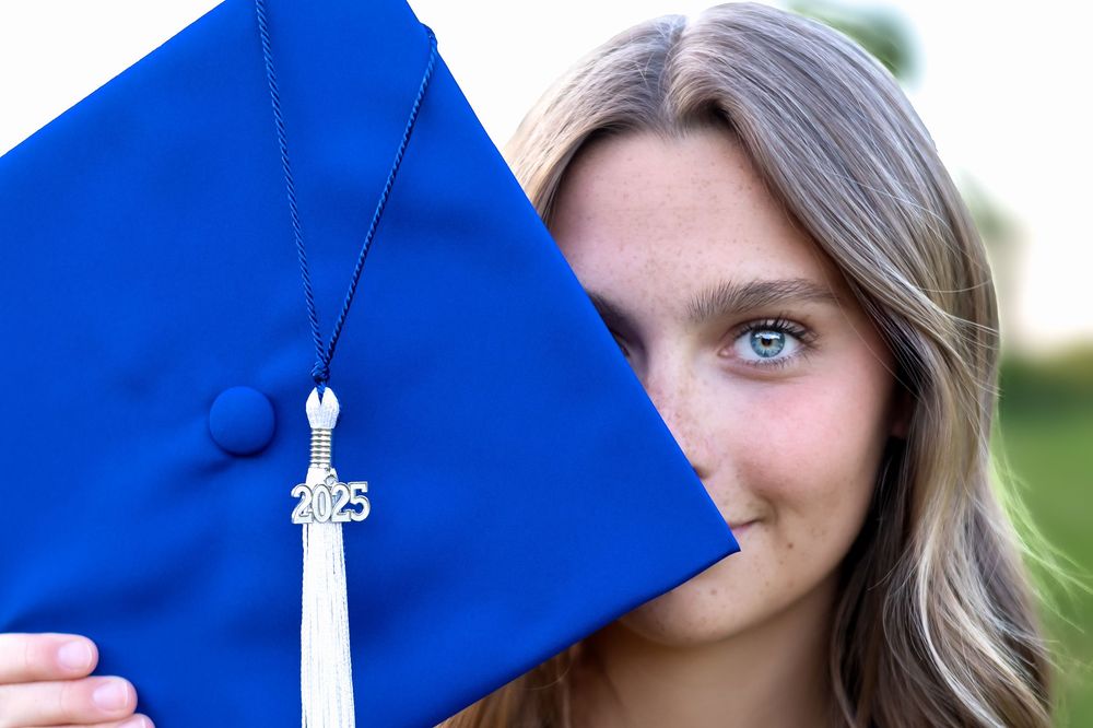 Oconee County senior posing with cap in front of one eye during golden hour session in Athens, GA.