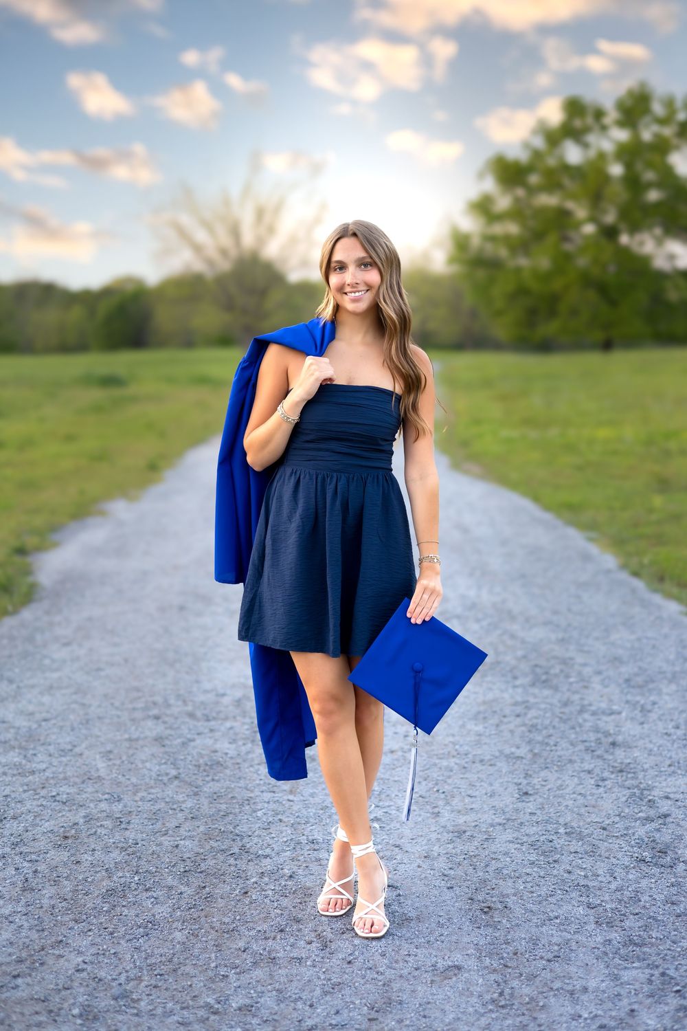 Graduation portrait of Oconee County High School senior with gown draped over shoulder on a gravel path at sunset in Athens, GA.