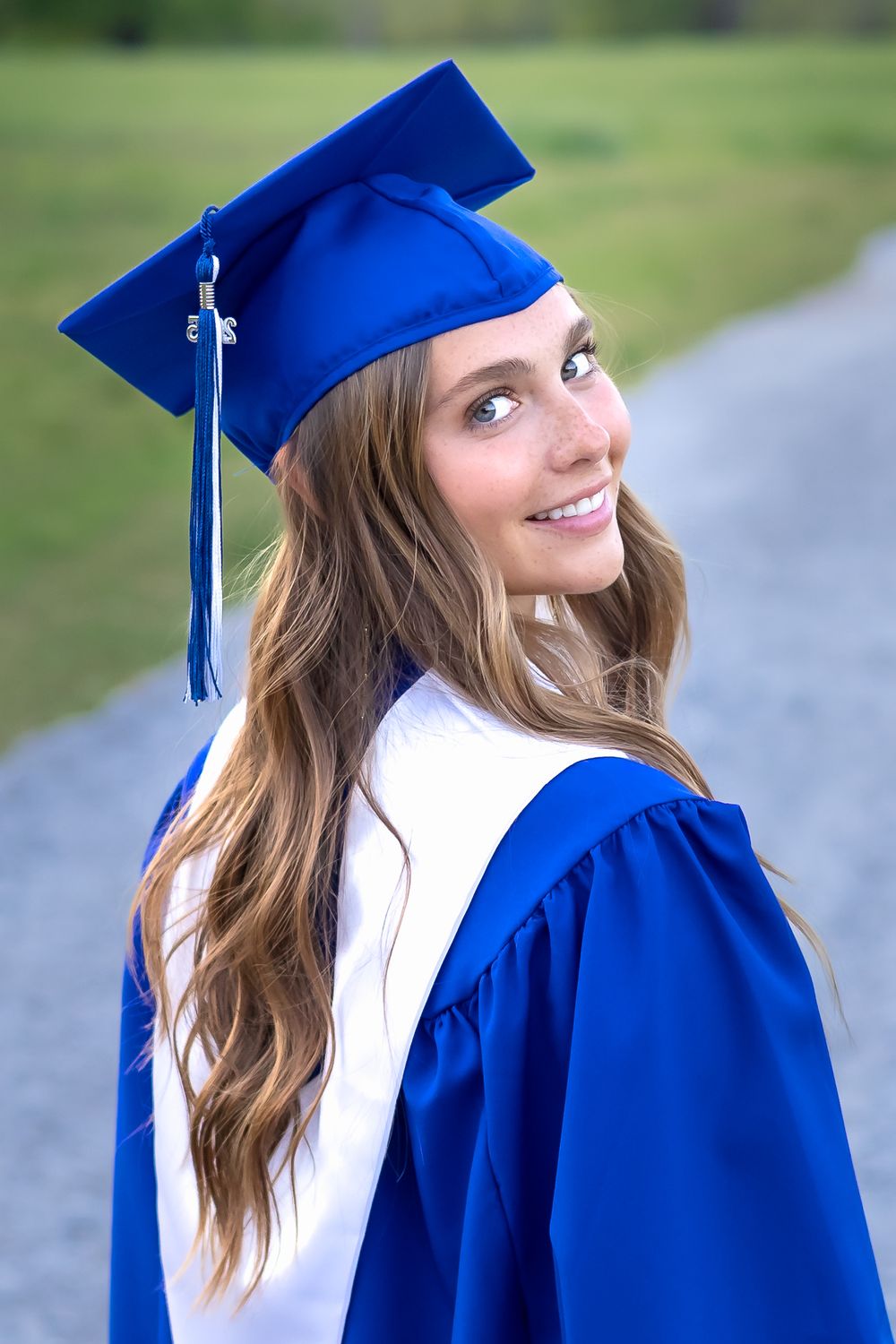 Outdoor senior session with OCHS graduate wearing cap and gown and standing on a gravel path in Athens, GA - Senior photographer in Athens