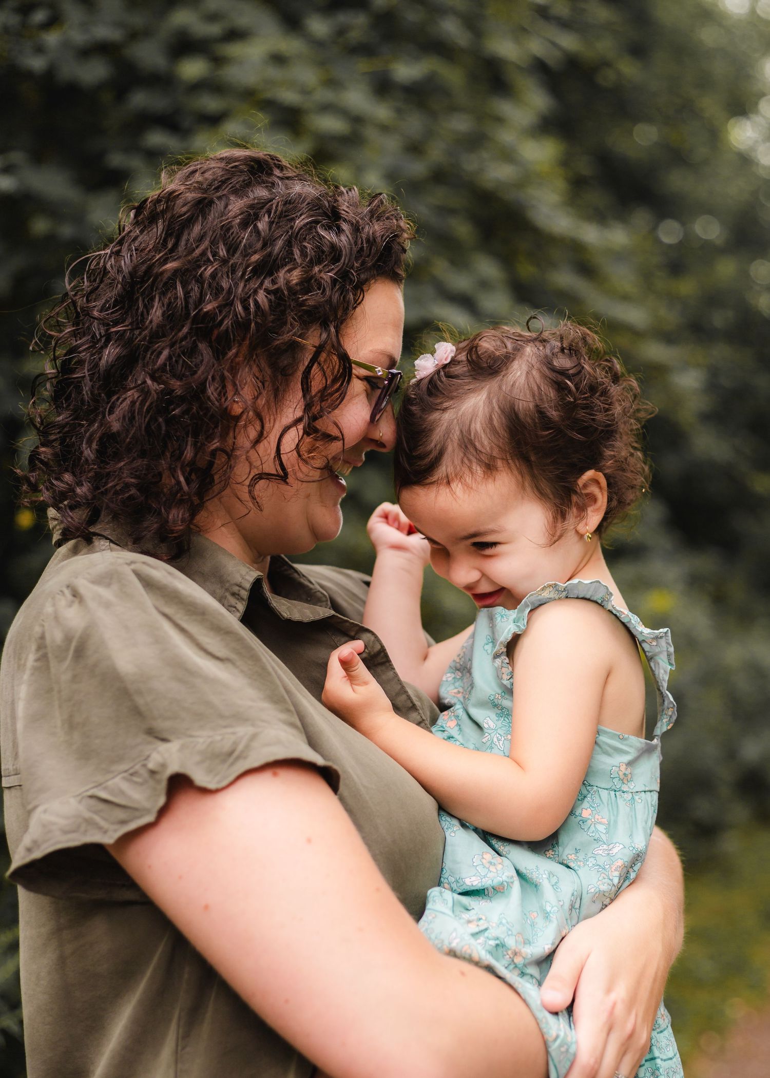 A joyful moment of laughter and bonding captured in natural lighting among green foliage outdoors.