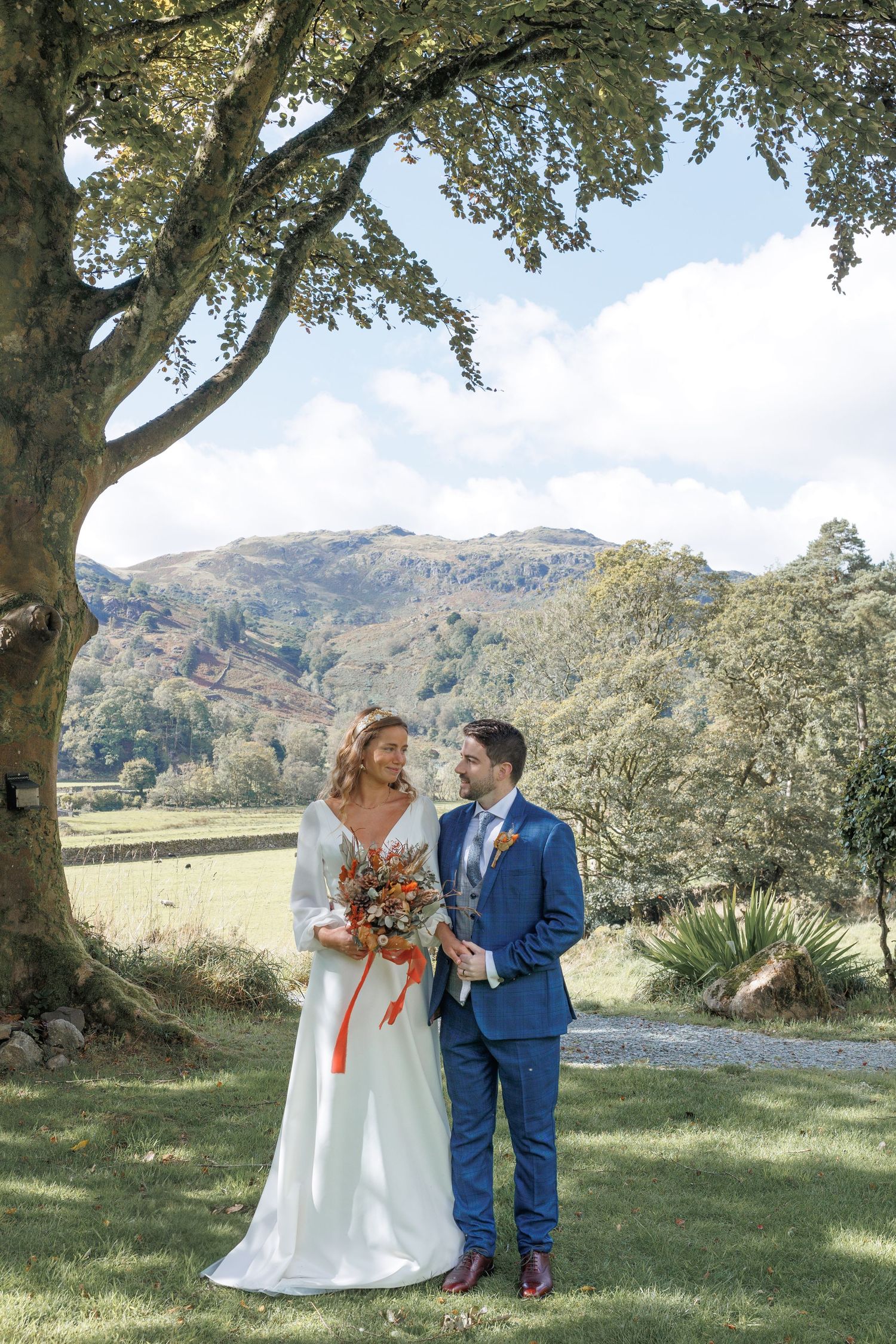 Beautiful wedding scene under sprawling oak trees with mountains and fields in the background.