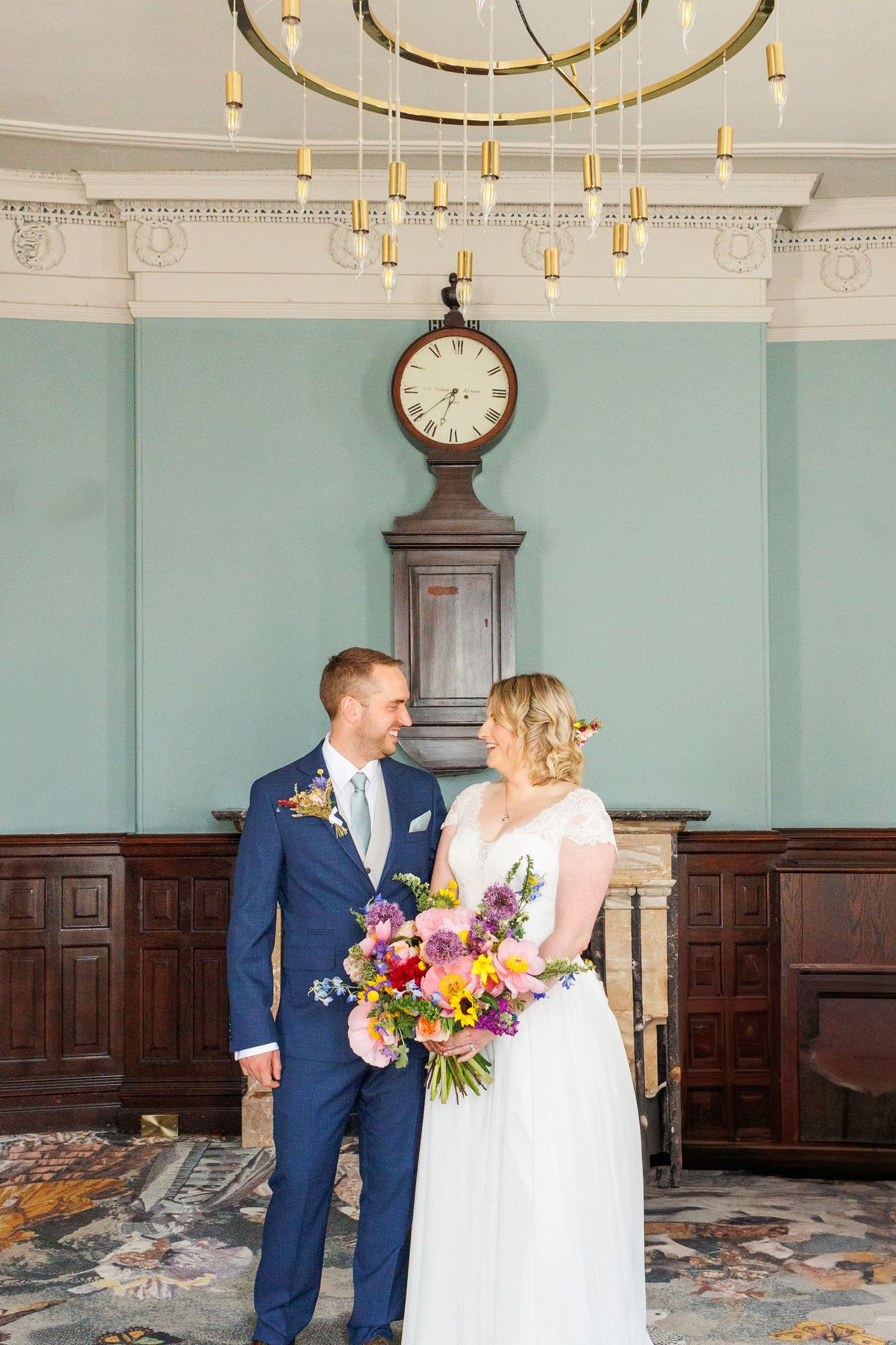 Elegant mint green room with vintage clock and ornate gold chandelier for wedding celebration.