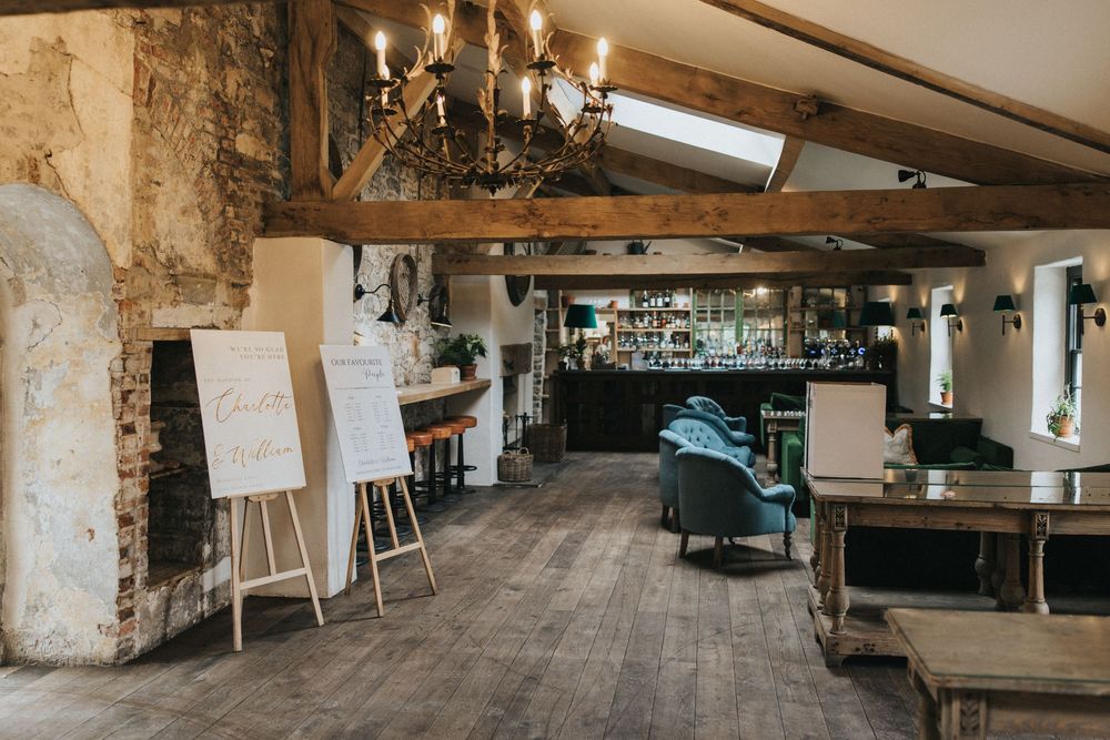 Rustic event venue interior features exposed brick walls and wooden beams with banquet tables and vintage lighting.