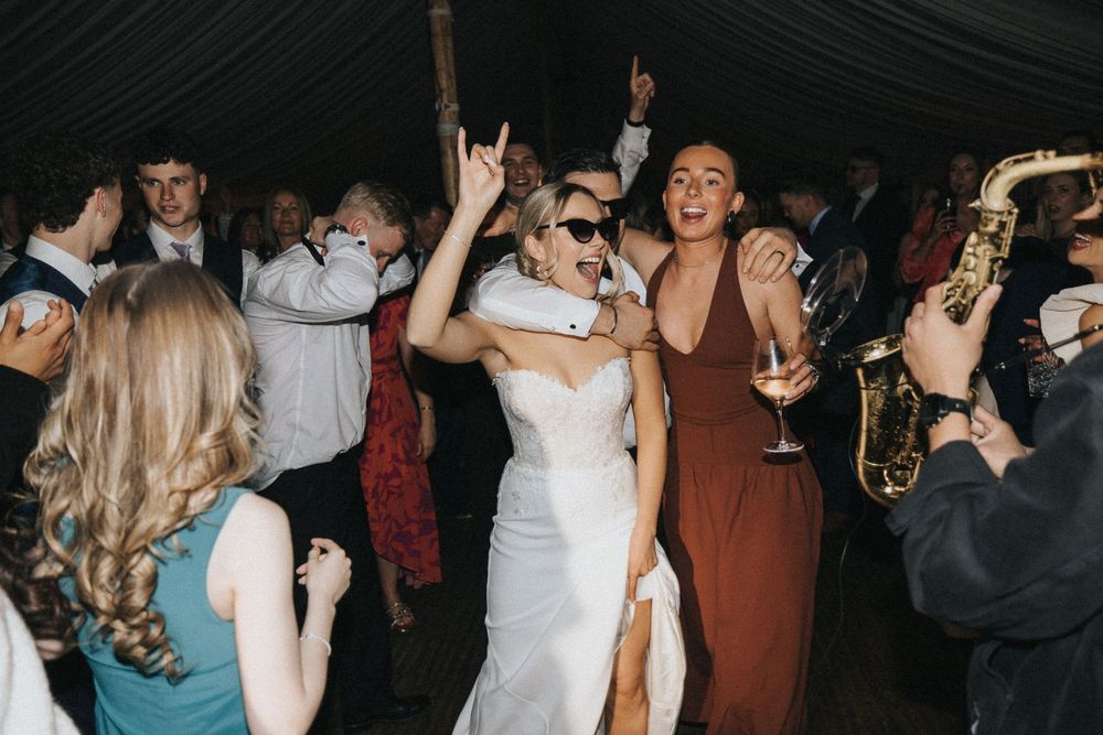 Wedding guests dancing and celebrating on a dance floor with energetic party atmosphere at a nighttime reception event.