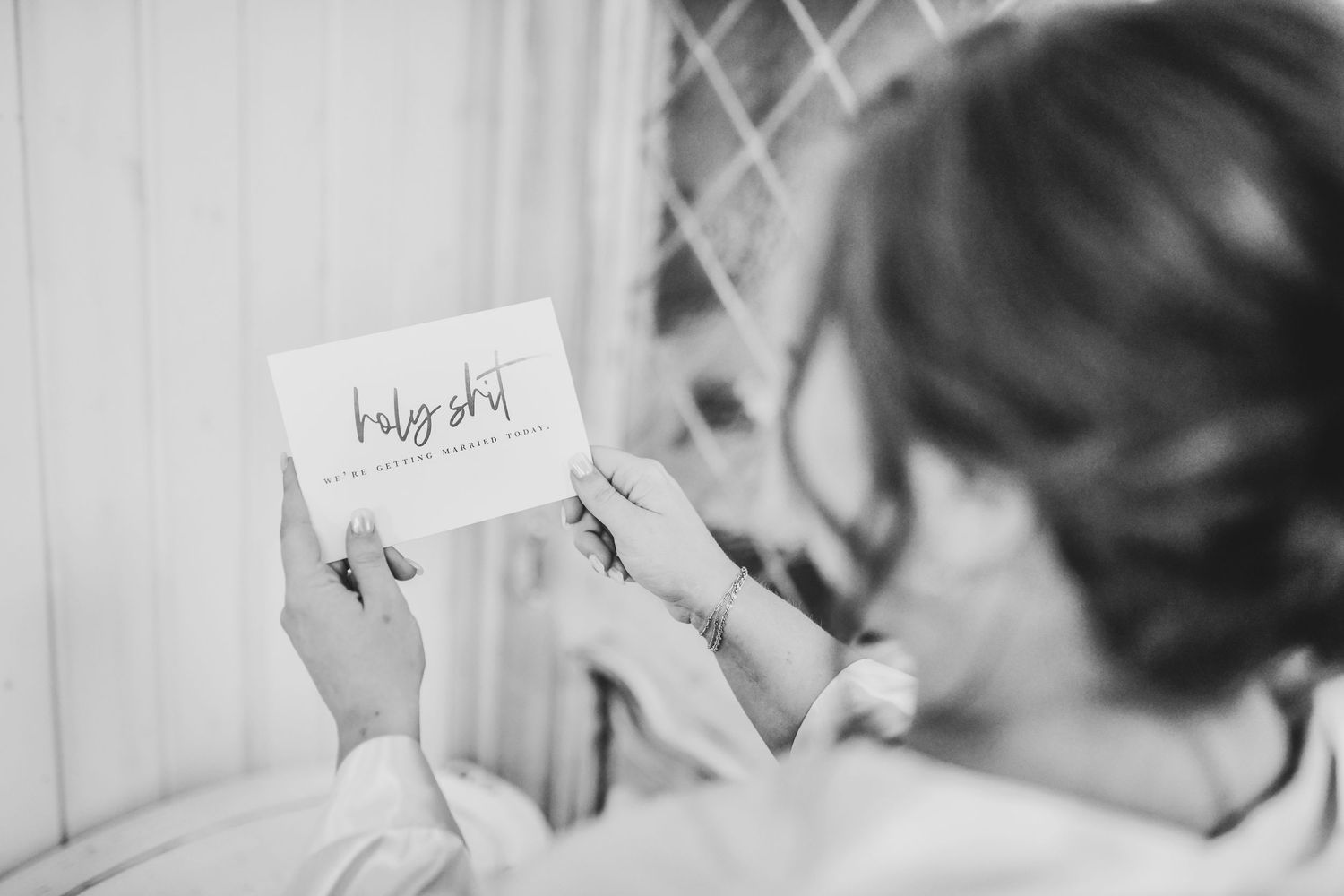 Bride reading groom’s letter near a window with natural light glowing on her face