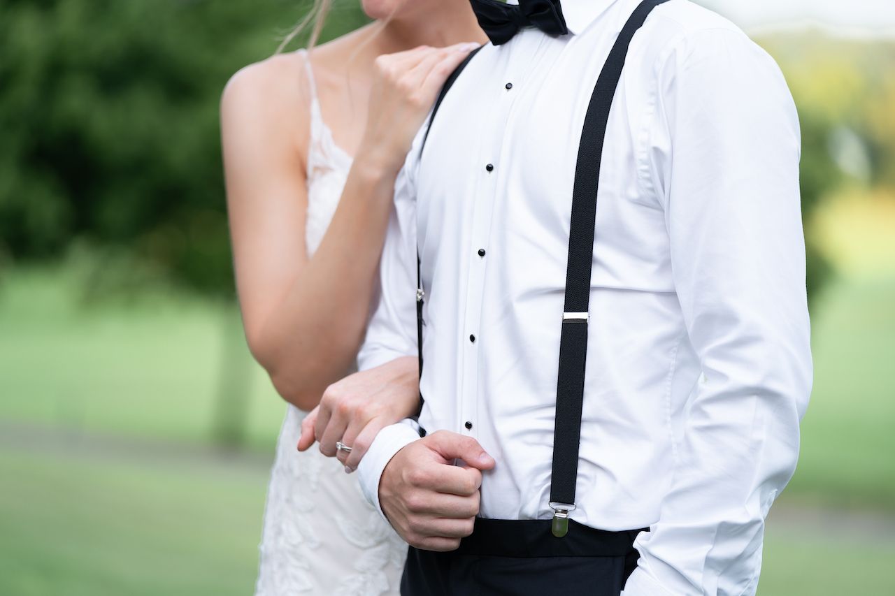 Classic groom's attire detail showing white shirt, black suspenders and bow tie.
