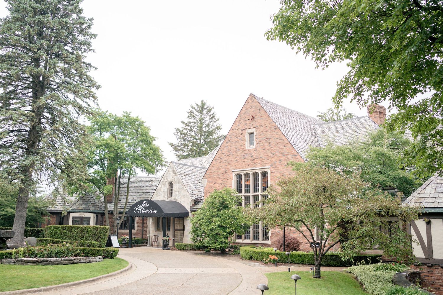 Exterior view of stone Tudor-style church building with landscaped grounds.