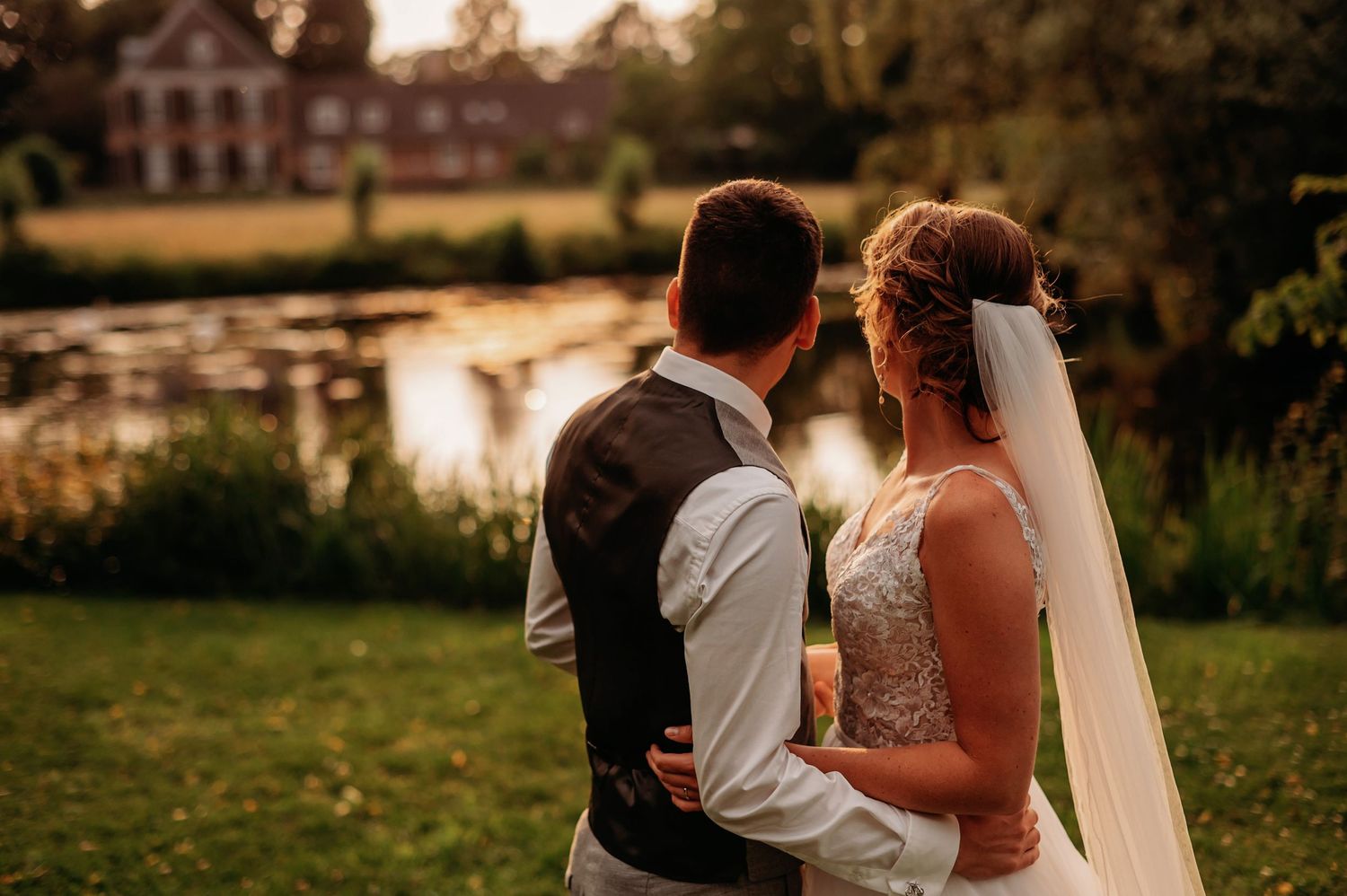 A couple shares a romantic moment at sunset during their outdoor countryside wedding celebration.