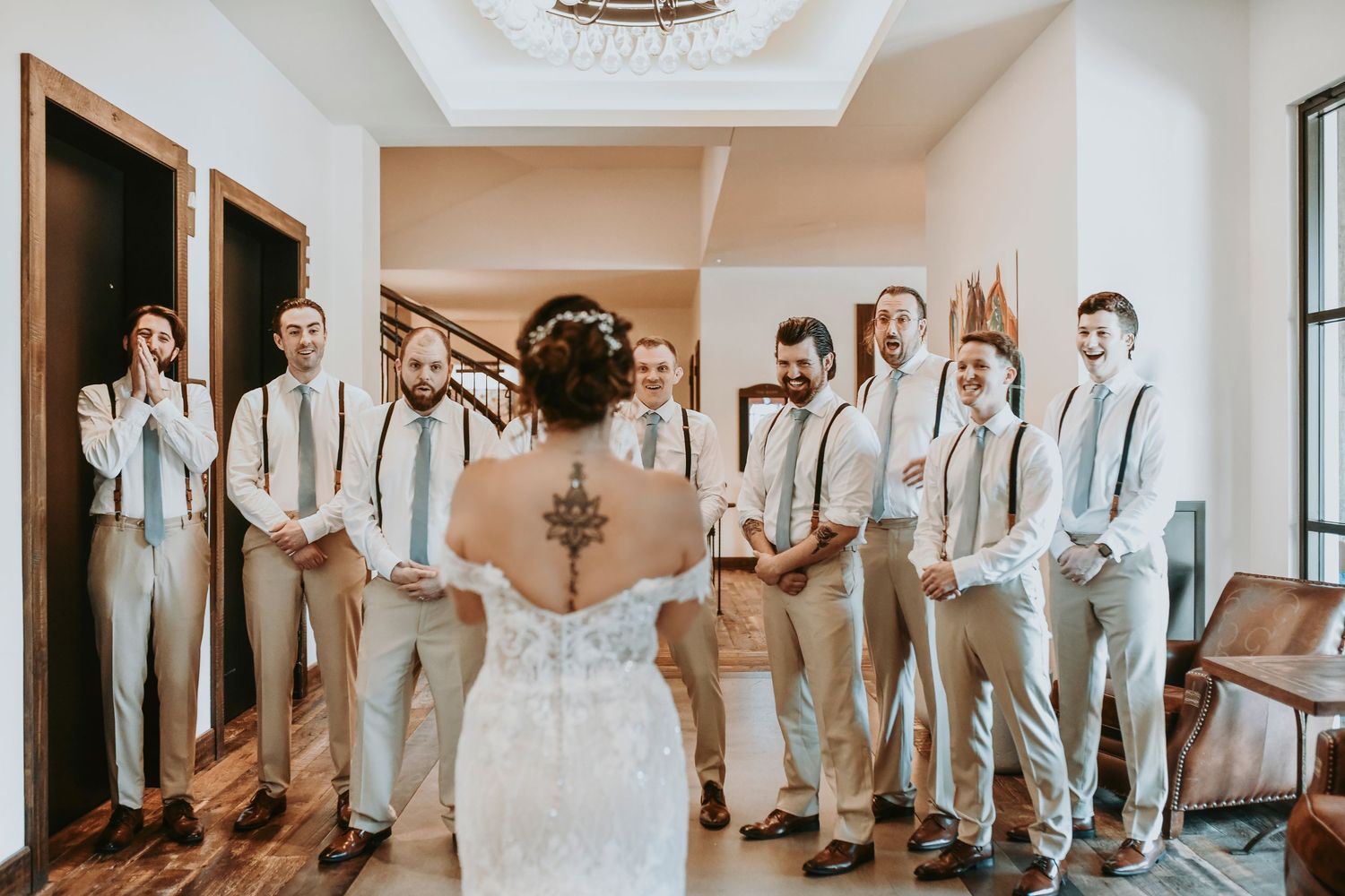 Group photo of groomsmen laughing together before ceremony as they look at the bride for the first time
