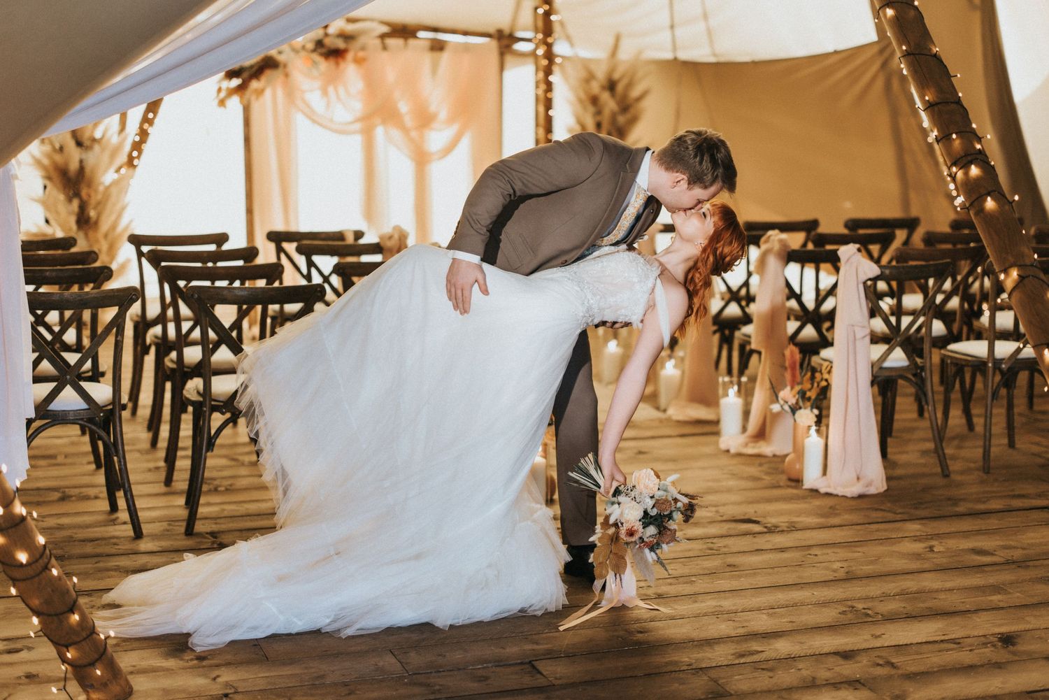 A romantic moment captured of wedding couple dancing inside a tent canopy with chairs lined up in the background at Nuddock Wood Lake.