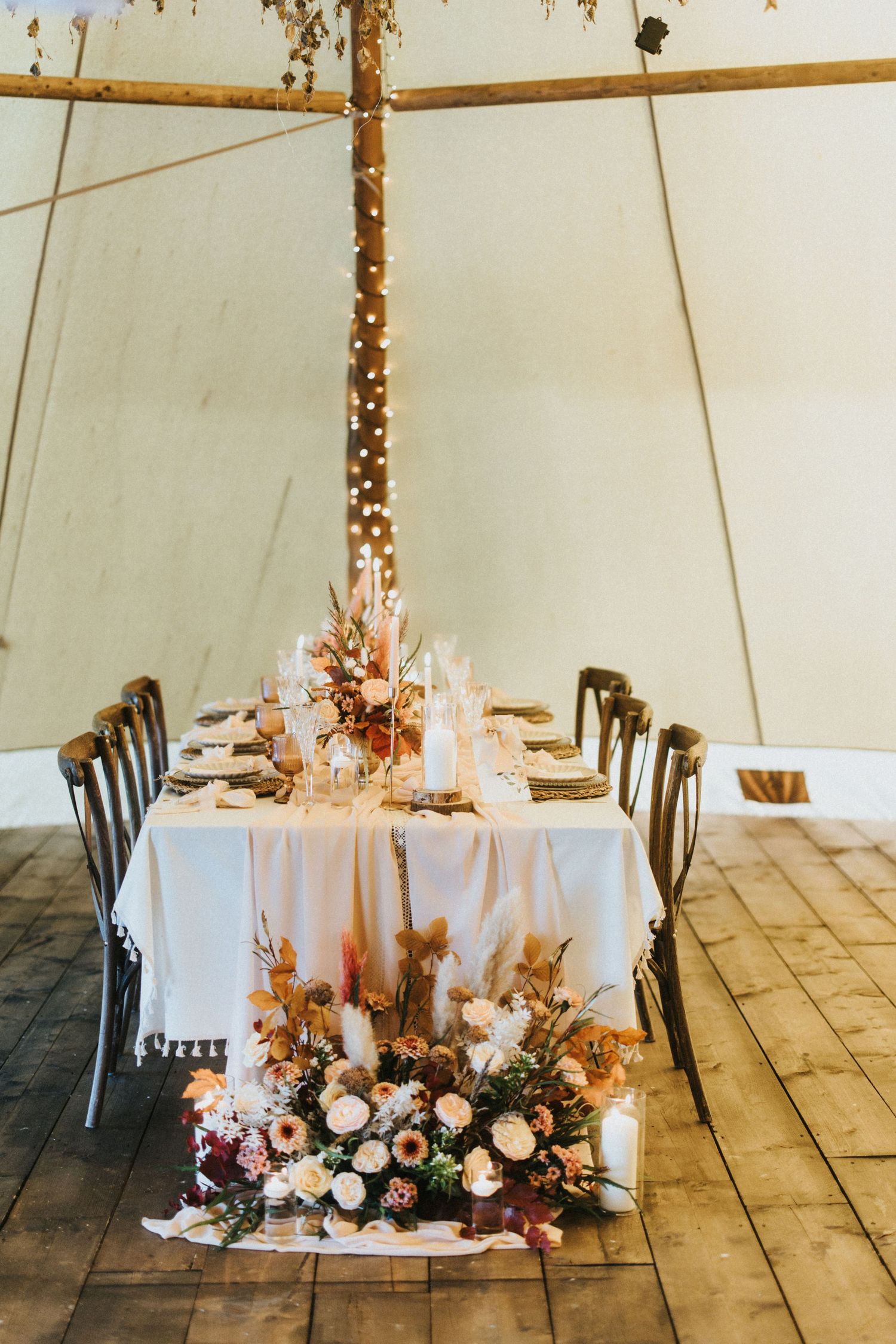 White event tent interior with elegant table settings and romantic floral centrepieces illuminated by warm candlelight at Nuddock Wood Lake.