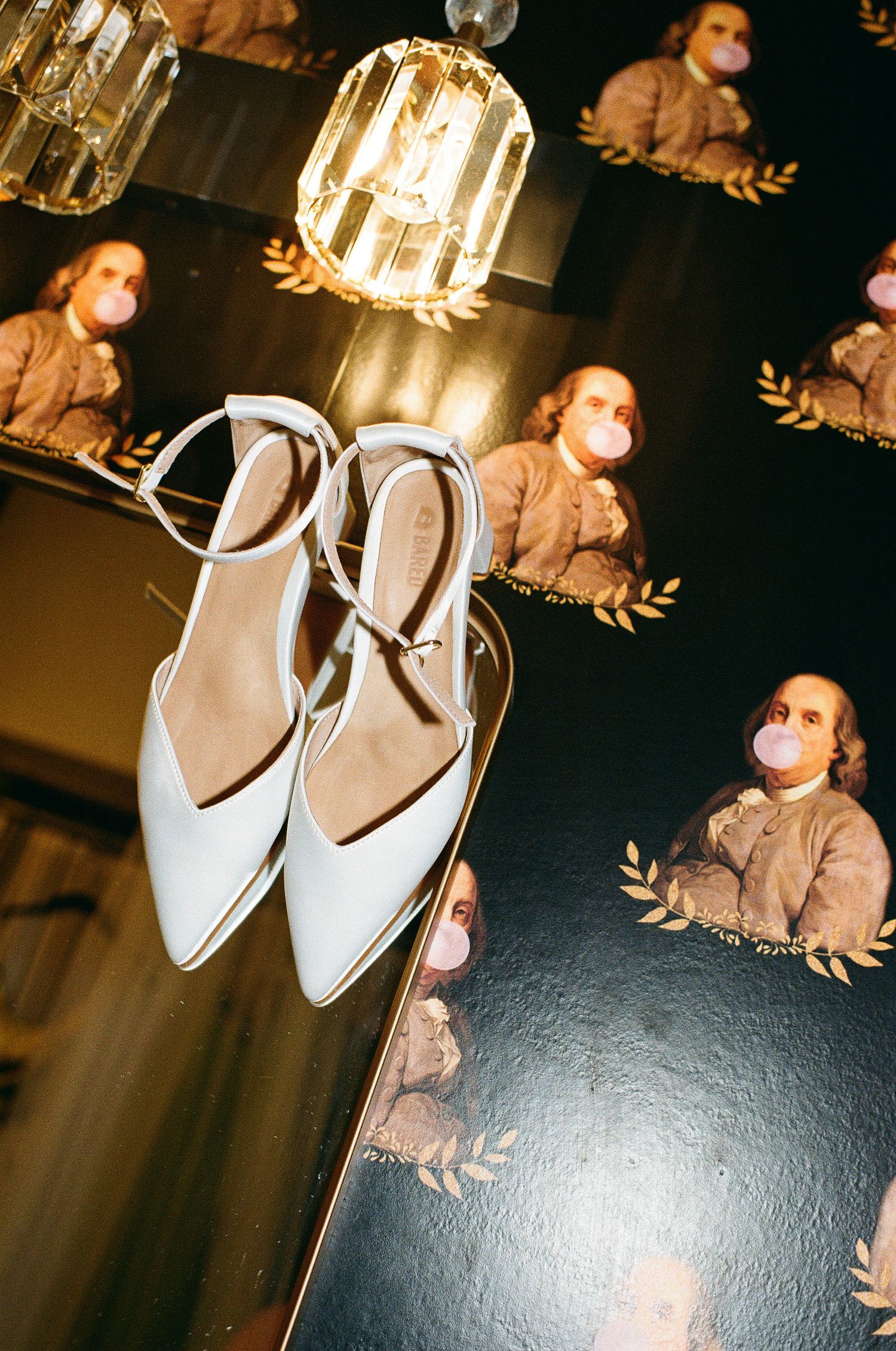 White ballet flats dance shoes hanging against dark background with soft lighting and reflective surface.
