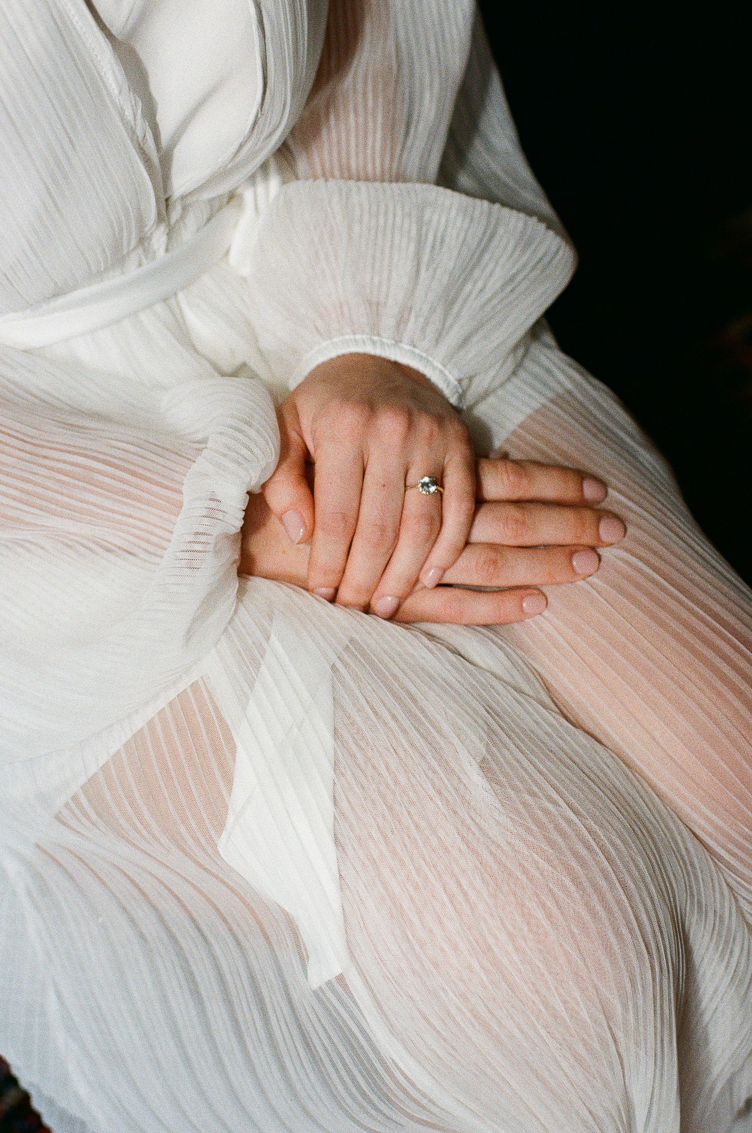 Hands tenderly entwined on soft white fabric in a gentle and intimate series of poses.