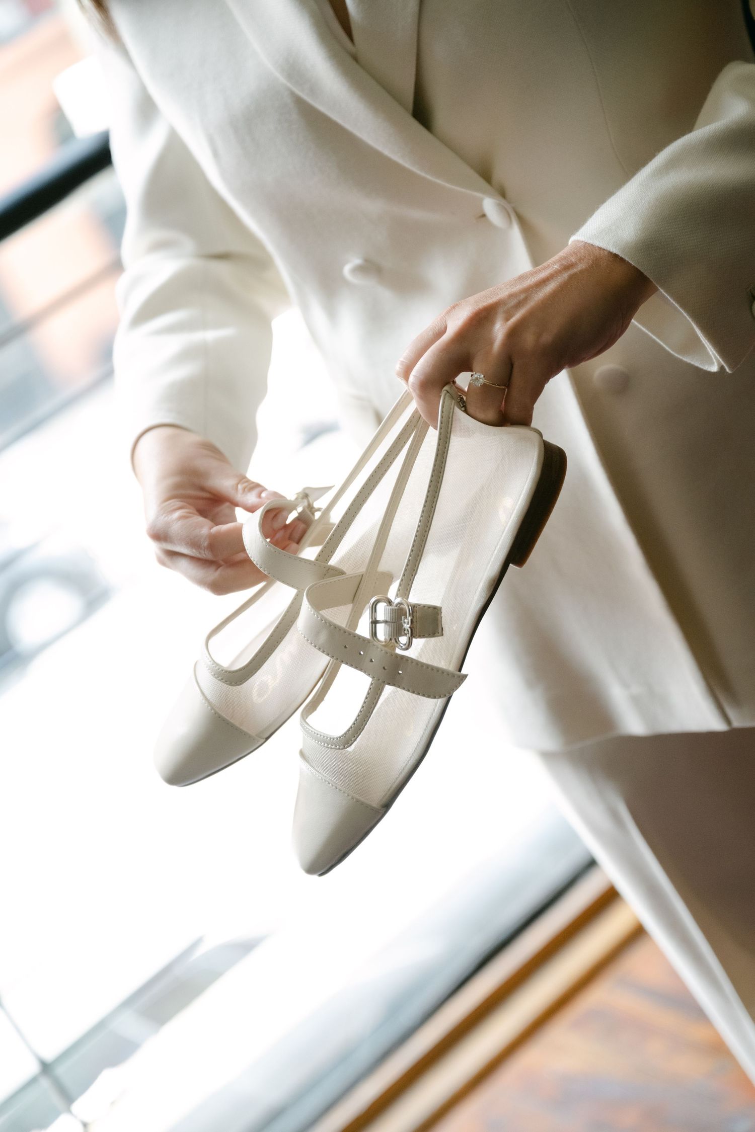 Close-up shots of hands adjusting elegant white shoes in natural lighting.