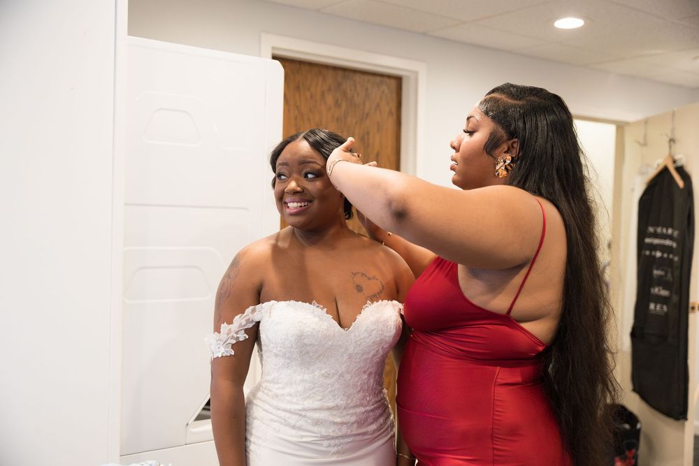 People in formal attire share joyful moments in a white room with decorative wall art.